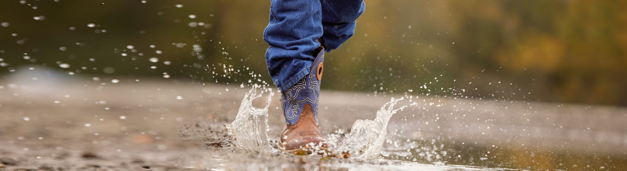 Close up of waterproof work boots stepping into a bubble of water.